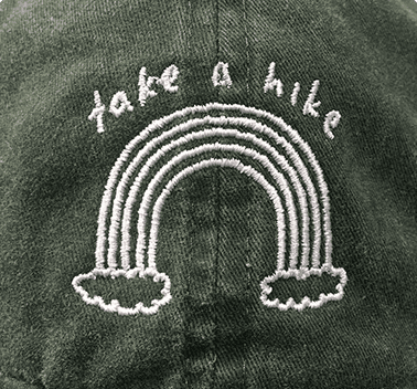 White flat embroidered rainbow design on a green hat