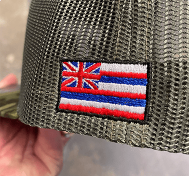 Hawaiian flag embroidered on the side of a mesh trucker hat