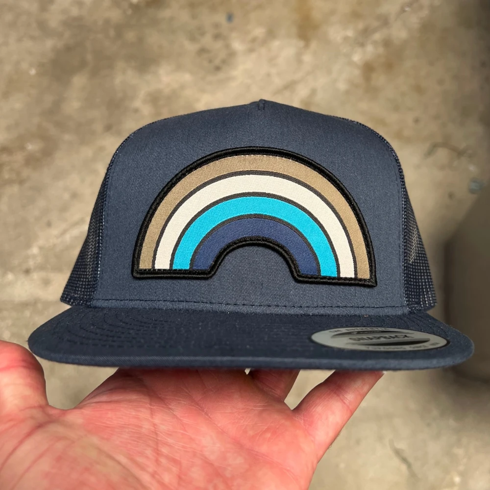 navy Yupoong 6006 mesh-back flat bill hat with rainbow-shaped woven patch