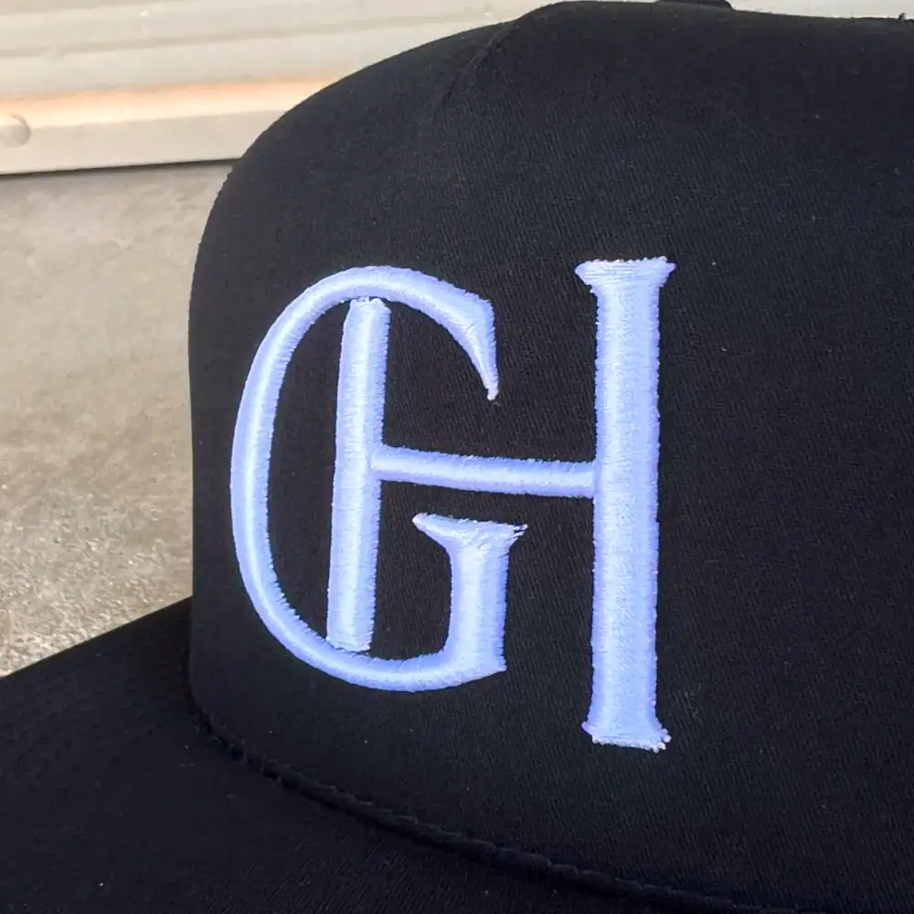 white 3D puff embroidered monogram on a black snapback