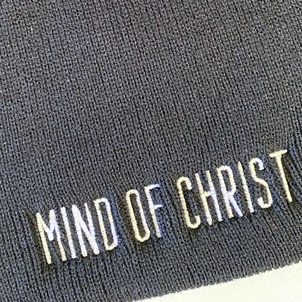 White text embroidered on a charcoal grey knit beanie