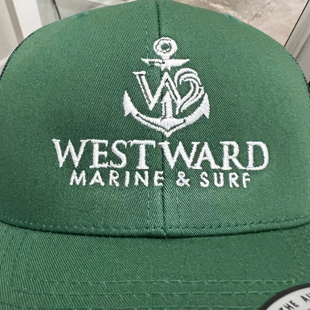 White anchor logo embroidered on a green trucker hat