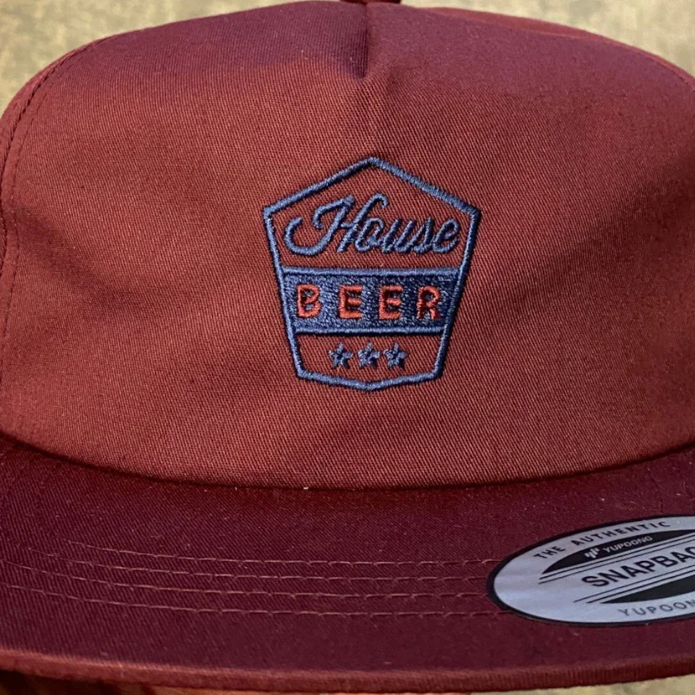 Two-color crest logo embroidered on a burgundy snapback