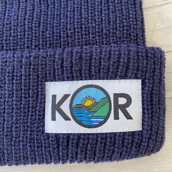woven label affixed to custom beanie hats in navy watchman cap style